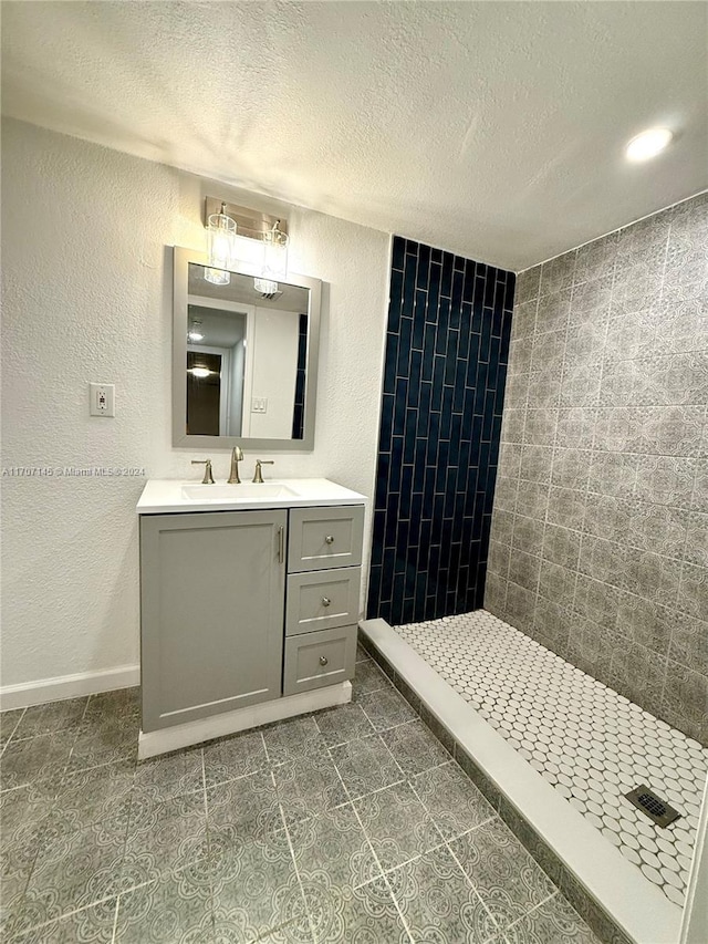 bathroom featuring tiled shower, a textured ceiling, and vanity