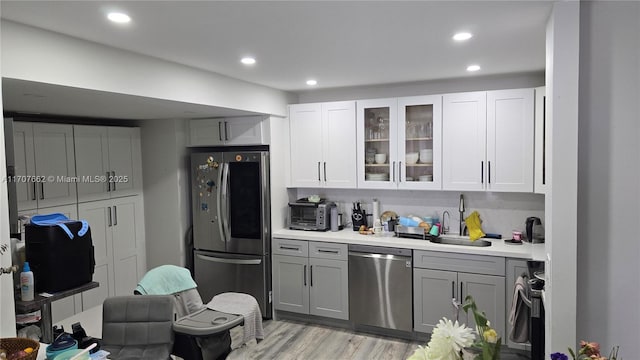 kitchen with gray cabinets, tasteful backsplash, sink, stainless steel appliances, and light hardwood / wood-style flooring