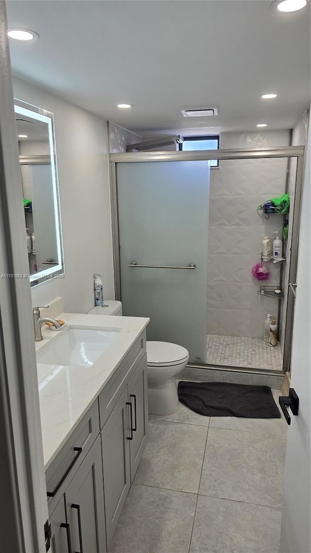 bathroom featuring tile patterned floors, vanity, toilet, and a shower with shower door