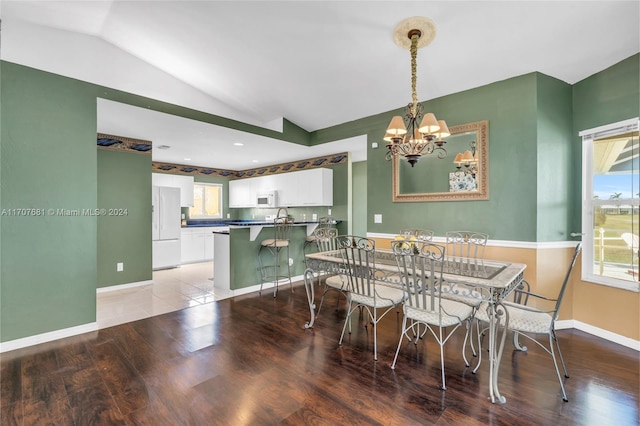 dining area featuring hardwood / wood-style floors, vaulted ceiling, and a notable chandelier