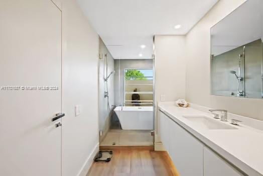 bathroom featuring hardwood / wood-style floors, vanity, and shower with separate bathtub