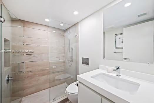 bathroom featuring vanity, toilet, and tiled shower