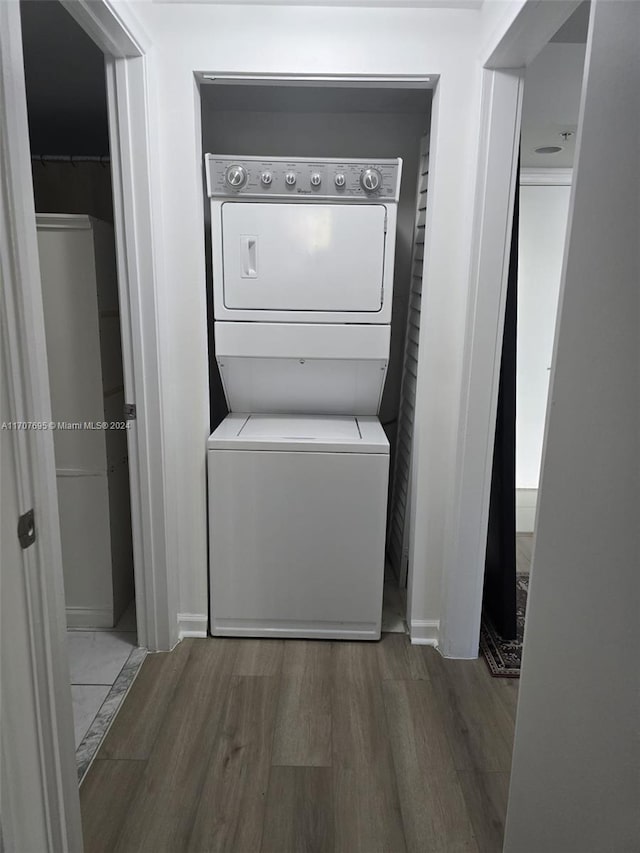 washroom featuring hardwood / wood-style flooring and stacked washer / drying machine