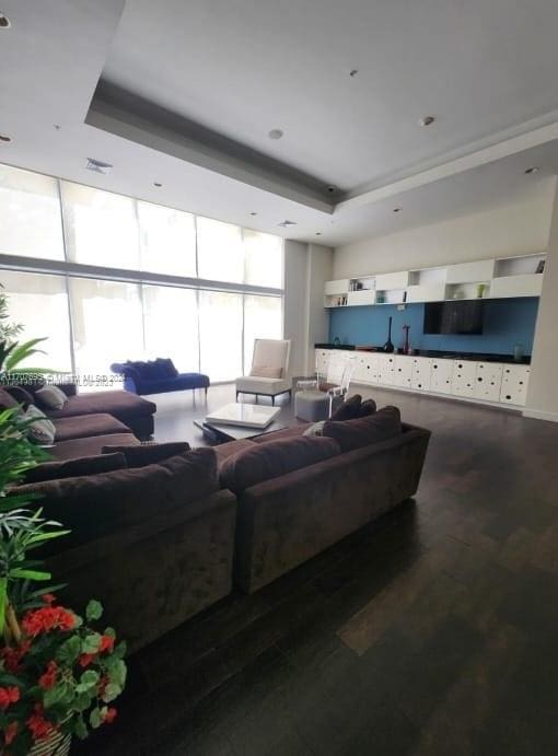 living room with a raised ceiling, floor to ceiling windows, and hardwood / wood-style floors