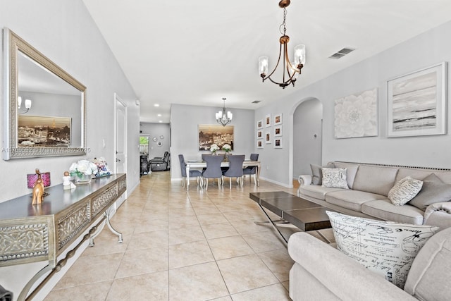 living area with arched walkways, light tile patterned floors, visible vents, a chandelier, and baseboards