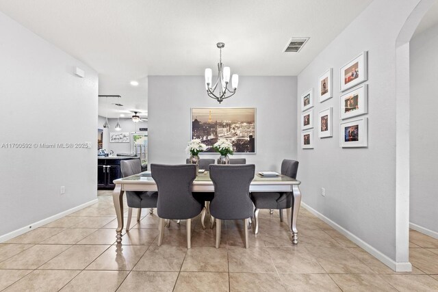 dining area featuring light tile patterned floors and ceiling fan with notable chandelier