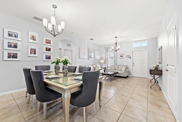 dining room featuring baseboards, visible vents, arched walkways, a notable chandelier, and light tile patterned flooring