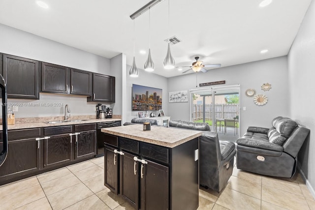 kitchen featuring pendant lighting, dishwasher, sink, light tile patterned floors, and a kitchen island