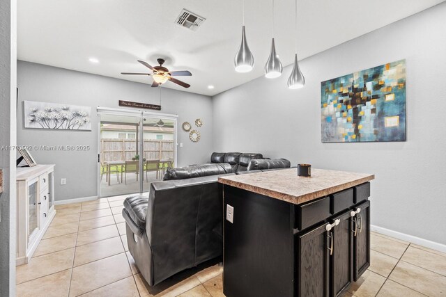 kitchen with pendant lighting, ceiling fan, a center island, and light tile patterned floors