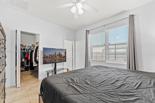 bedroom featuring light tile patterned floors, a closet, a spacious closet, and ceiling fan