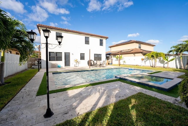 back of property with a swimming pool with hot tub and a patio