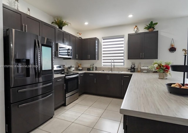 kitchen with dark brown cabinetry, sink, light tile patterned floors, and appliances with stainless steel finishes