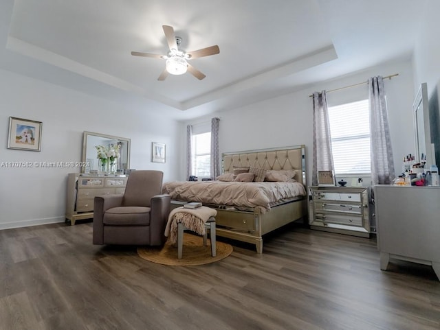 bedroom with ceiling fan, dark hardwood / wood-style floors, and a raised ceiling