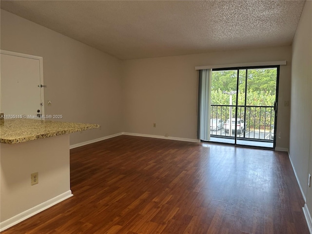 unfurnished room with a textured ceiling and dark wood-type flooring