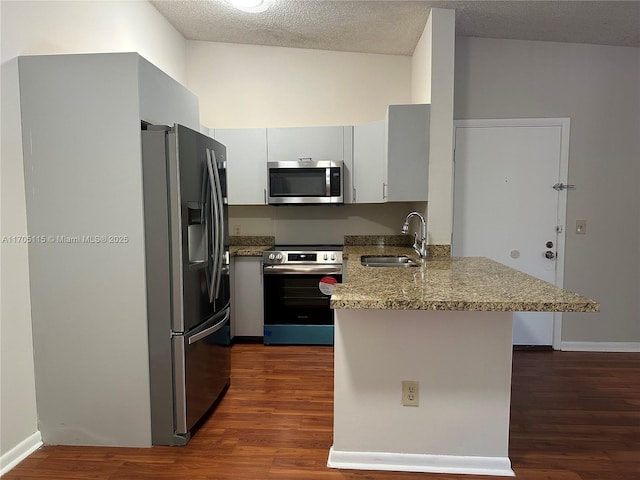 kitchen with kitchen peninsula, a textured ceiling, stainless steel appliances, sink, and white cabinets