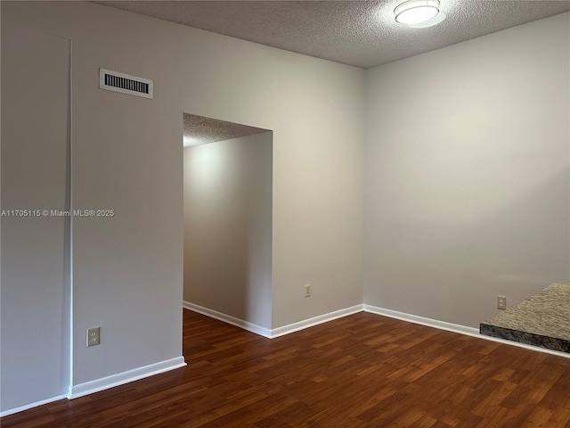 empty room featuring dark wood-type flooring and a textured ceiling