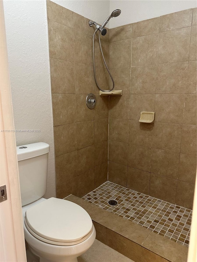 bathroom with a tile shower and toilet