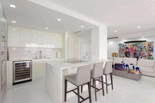 kitchen featuring black electric stovetop, backsplash, beverage cooler, sink, and white cabinetry