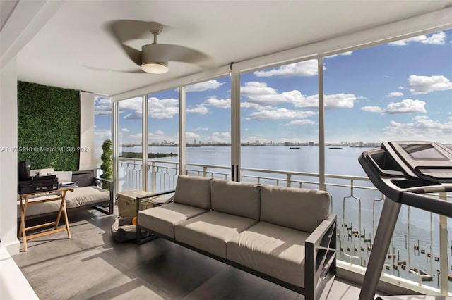 sunroom / solarium with ceiling fan and a water view