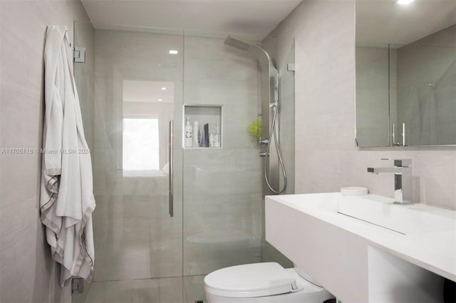 bathroom featuring vanity, toilet, tiled shower, and tile walls