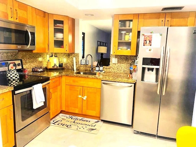 kitchen featuring sink, stainless steel appliances, tasteful backsplash, stone countertops, and light tile patterned floors