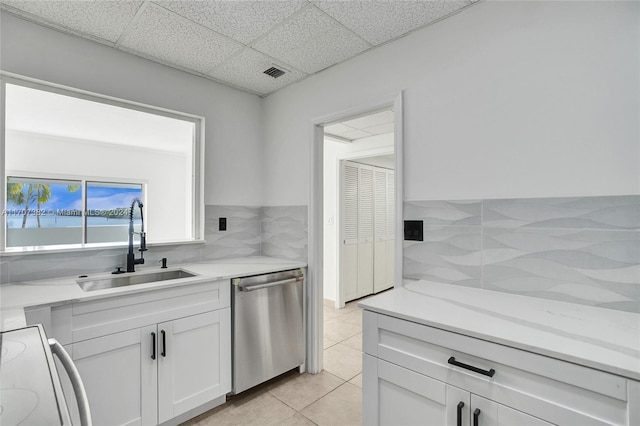 kitchen with stove, stainless steel dishwasher, sink, white cabinets, and light tile patterned flooring