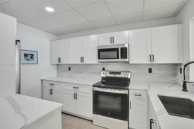 kitchen featuring white cabinetry, sink, light tile patterned floors, and stainless steel appliances