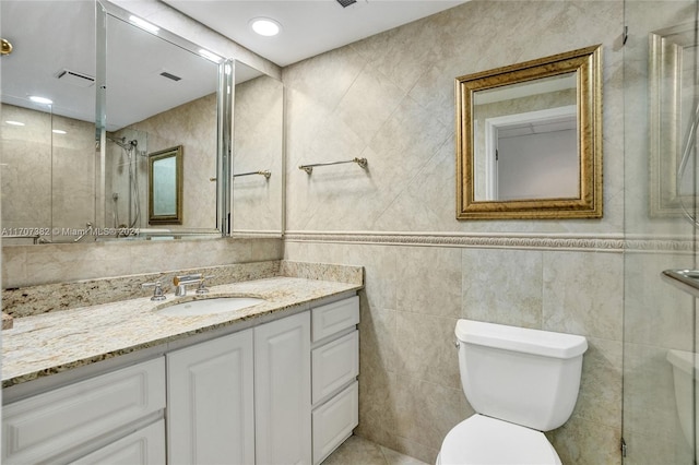 bathroom featuring vanity, toilet, and tile walls