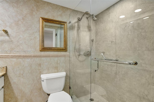 bathroom featuring a shower with door, vanity, tile walls, and toilet