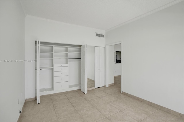 unfurnished bedroom featuring a textured ceiling, ornamental molding, and light tile patterned flooring