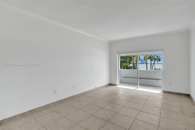 empty room featuring a textured ceiling, light tile patterned floors, and ornamental molding