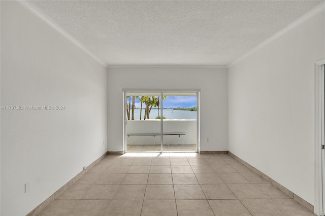 spare room featuring ornamental molding, a textured ceiling, and light tile patterned floors