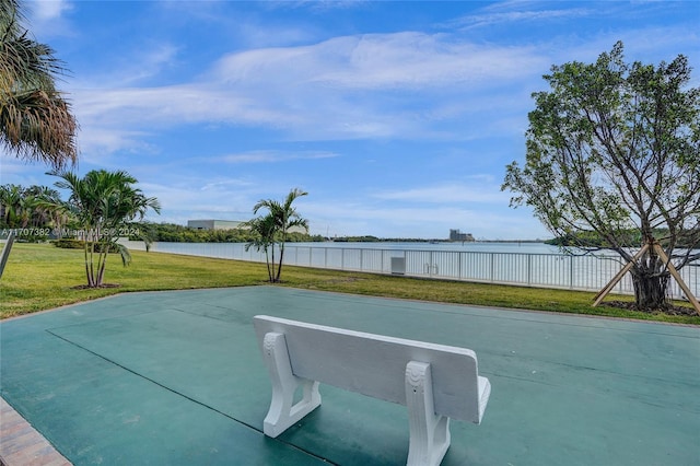 view of basketball court with a yard and a water view