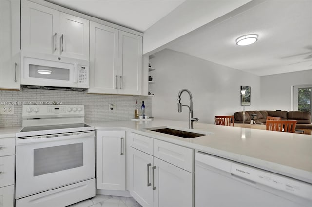 kitchen with white appliances, white cabinets, sink, tasteful backsplash, and kitchen peninsula