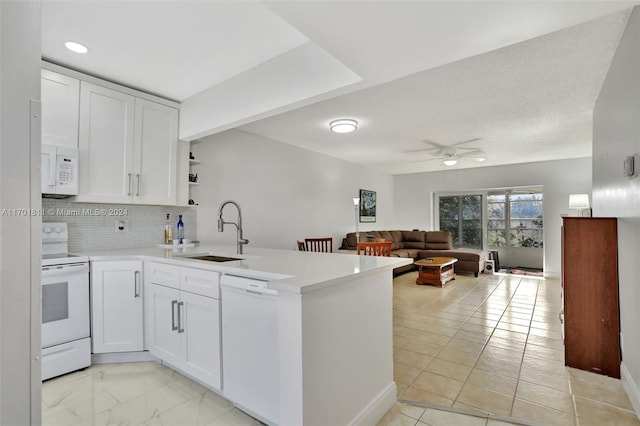 kitchen with kitchen peninsula, sink, white cabinets, and white appliances