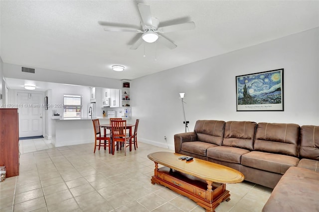 living room featuring ceiling fan, light tile patterned floors, and a textured ceiling