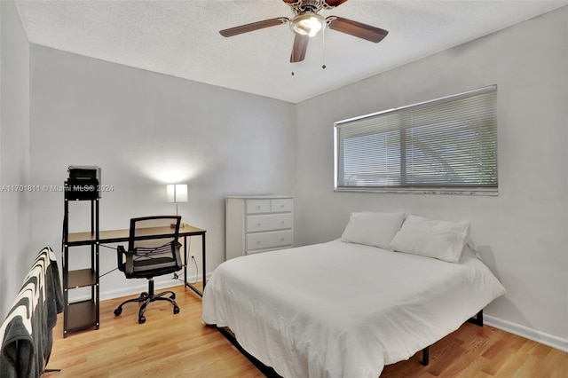 bedroom featuring hardwood / wood-style flooring, ceiling fan, and a textured ceiling