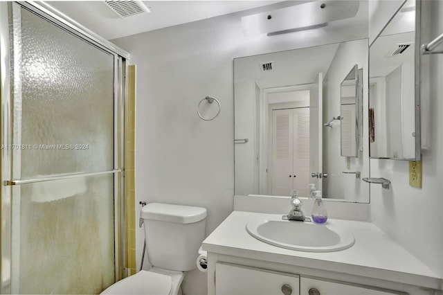 bathroom with vanity, toilet, and a shower with shower door