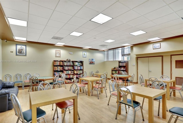 dining area featuring a paneled ceiling, crown molding, and light wood-type flooring