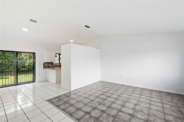 empty room featuring light tile patterned floors and lofted ceiling