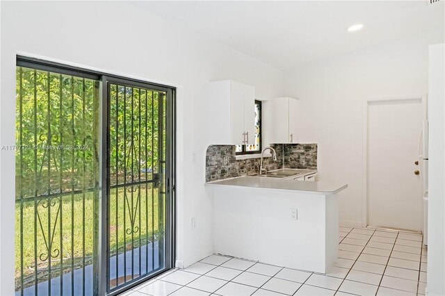 interior space featuring kitchen peninsula, plenty of natural light, white cabinetry, and sink