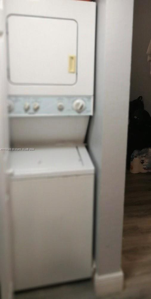 laundry area featuring hardwood / wood-style floors and stacked washer / dryer