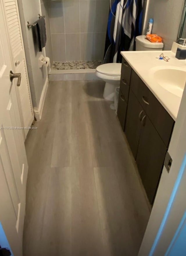 bathroom with hardwood / wood-style floors, vanity, curtained shower, and toilet