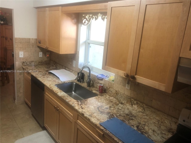 kitchen with sink, black dishwasher, tasteful backsplash, light stone counters, and light tile patterned floors