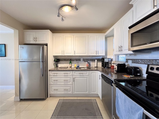 kitchen featuring white cabinetry, stainless steel appliances, tasteful backsplash, dark stone counters, and light tile patterned floors