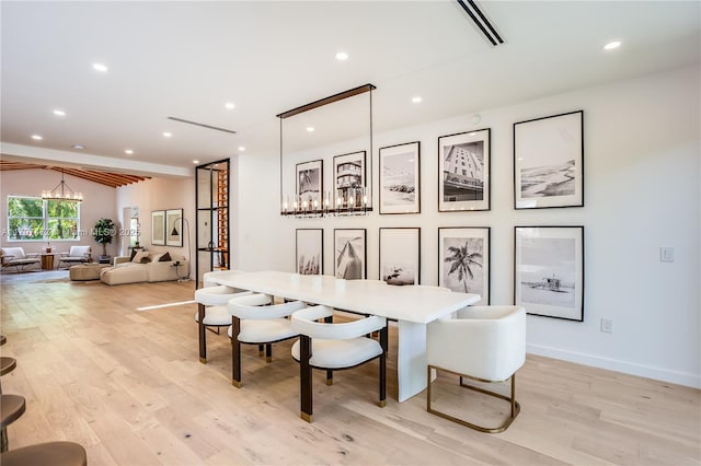 dining space with an inviting chandelier, lofted ceiling with beams, and light hardwood / wood-style floors