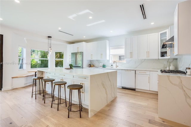 kitchen with light stone countertops, appliances with stainless steel finishes, pendant lighting, white cabinets, and a center island