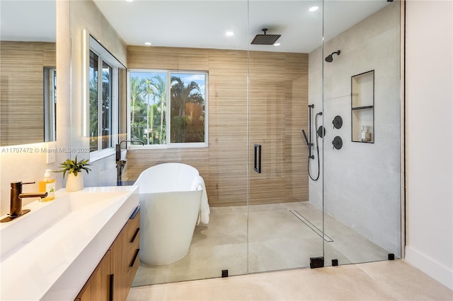 bathroom with tile patterned floors, vanity, separate shower and tub, and tile walls