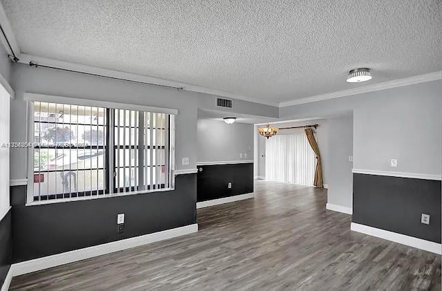 unfurnished room featuring ornamental molding, a textured ceiling, an inviting chandelier, and dark wood-type flooring