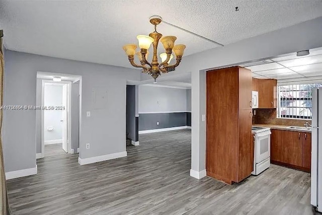 kitchen featuring pendant lighting, white appliances, hardwood / wood-style flooring, a textured ceiling, and a chandelier